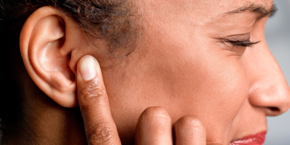 Closeup of side of a person's face while the person's finger is on the ear.